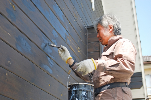 外壁塗装を長持ちさせるために塗り足している男性